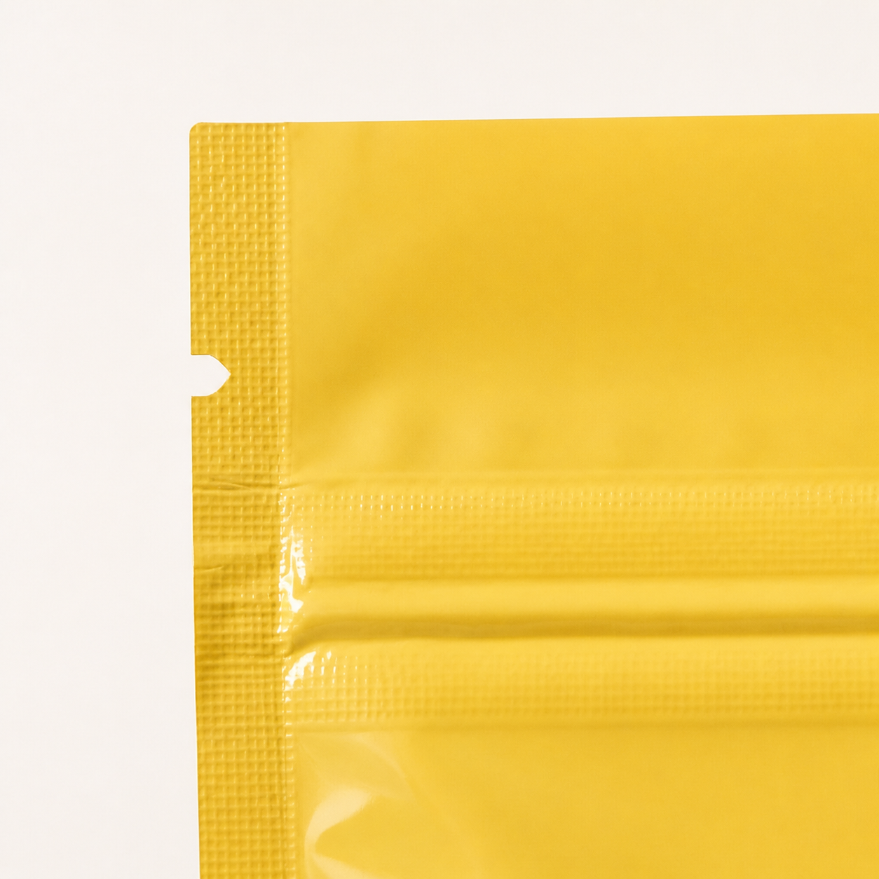 Close-up of an easy-tear notch on a yellow zipper pouch